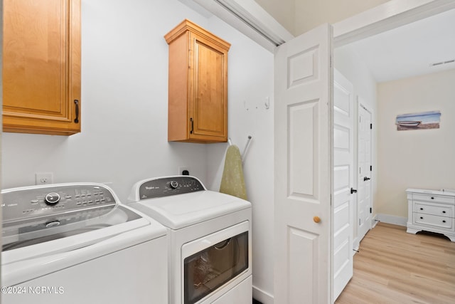 laundry area featuring light hardwood / wood-style flooring, cabinets, and washing machine and dryer