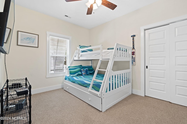 bedroom featuring light colored carpet, ceiling fan, and a closet