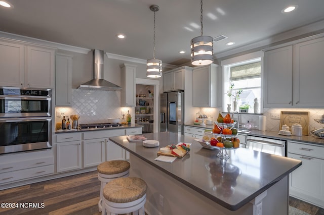 kitchen with appliances with stainless steel finishes, tasteful backsplash, a center island, and wall chimney exhaust hood