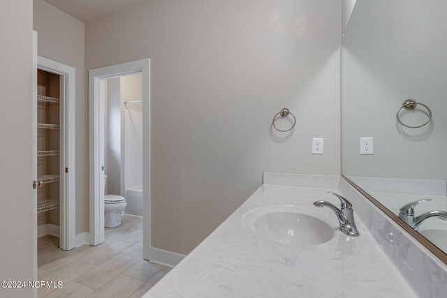 bathroom with vanity with extensive cabinet space, toilet, and tile floors