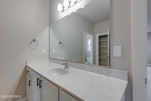 bathroom with toilet and vanity with extensive cabinet space