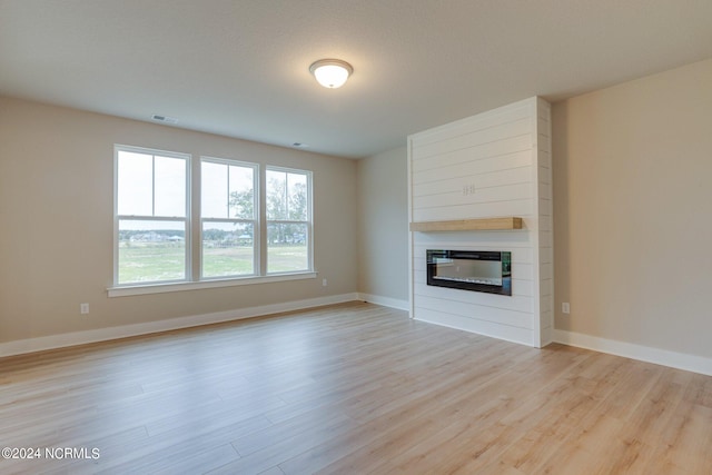 unfurnished living room featuring light hardwood / wood-style floors and a large fireplace