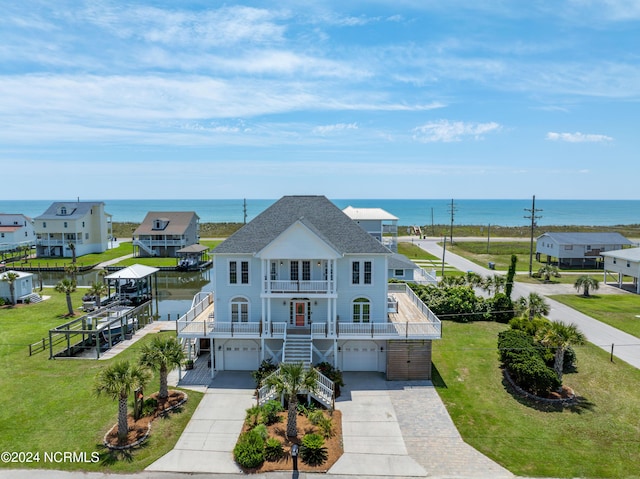 view of front of property featuring a water view, stairway, a balcony, a garage, and a front lawn