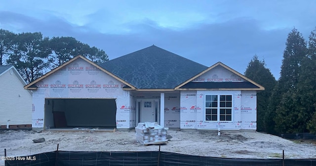 property in mid-construction featuring a garage and roof with shingles