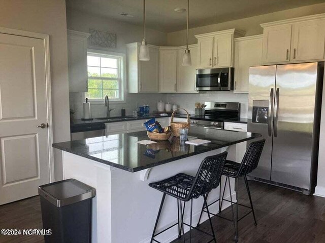 kitchen with white cabinetry, stainless steel appliances, decorative backsplash, dark hardwood / wood-style flooring, and a center island