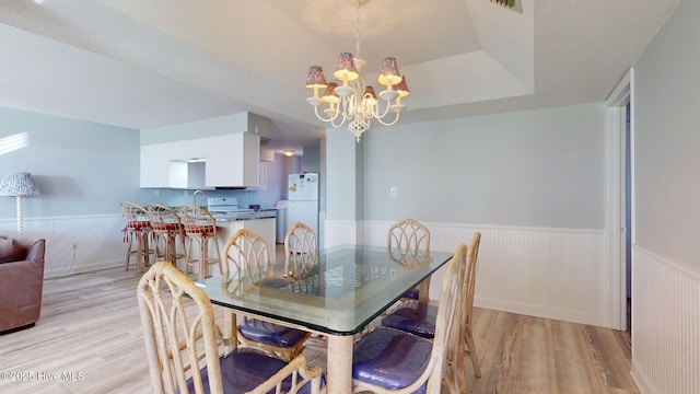 dining area featuring a chandelier, light hardwood / wood-style floors, a raised ceiling, and sink