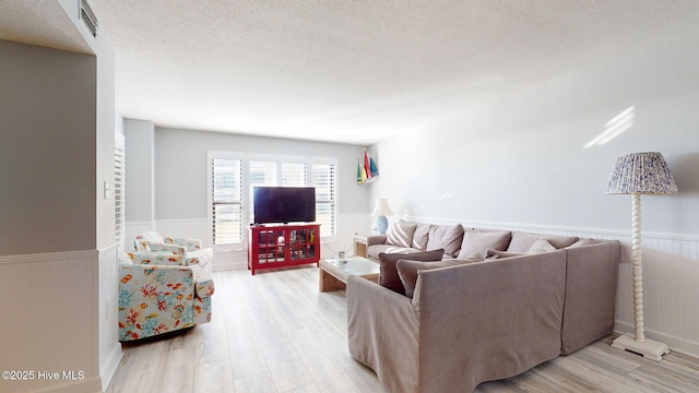 living room with a textured ceiling and light wood-type flooring