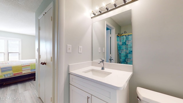 bathroom with a shower with shower curtain, a textured ceiling, vanity, hardwood / wood-style flooring, and toilet