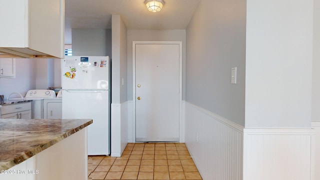 kitchen featuring light stone countertops, white cabinets, light tile patterned floors, and white refrigerator