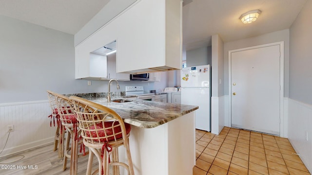 kitchen featuring white appliances, white cabinets, sink, washing machine and dryer, and kitchen peninsula