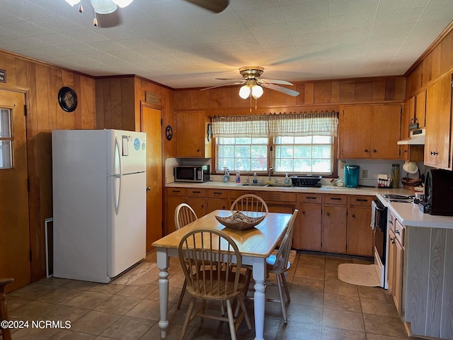 kitchen with ceiling fan, light tile floors, electric stove, white fridge, and wooden walls