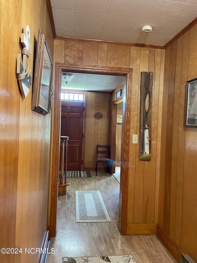 corridor with ornamental molding, wood walls, and wood-type flooring