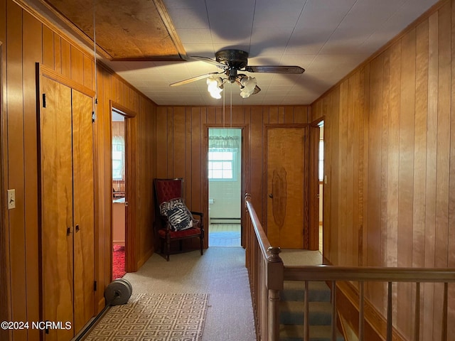 corridor featuring wood walls, carpet flooring, and a baseboard heating unit