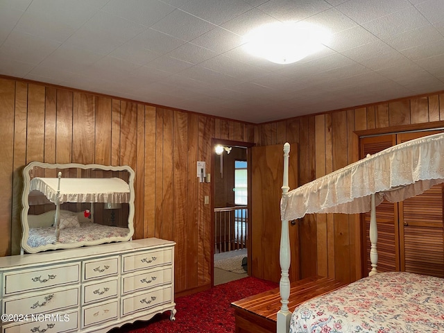 bedroom featuring wooden walls and dark carpet