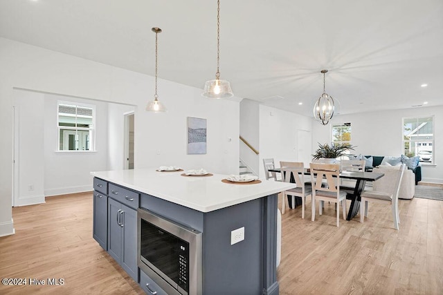 1134 Trisail Ter, Wilmington, NC 28412 - kitchen with built in microwave, gray cabinetry, light countertops, light wood-style floors, and decorative light fixtures