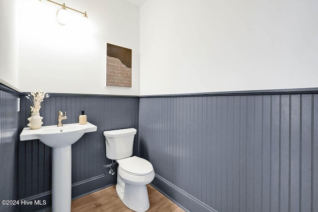 1134 Trisail Ter, Wilmington, NC 28412 - half bath with a wainscoted wall, wood finished floors, toilet, a sink, and baseboards