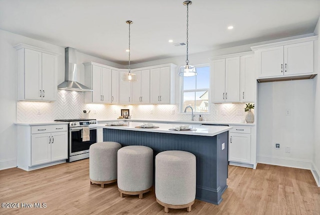 1134 Trisail Ter, Wilmington, NC 28412 - kitchen with stainless steel range with gas stovetop, wall chimney exhaust hood, a center island, white cabinets, and recessed lighting