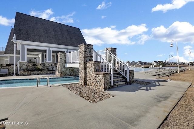 view of swimming pool featuring a water view and a patio area