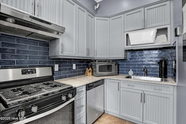 kitchen with sink, backsplash, light tile patterned floors, light stone counters, and stainless steel appliances