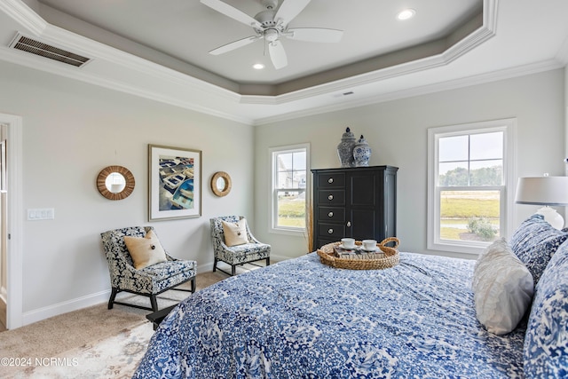 carpeted bedroom with ceiling fan, a tray ceiling, and ornamental molding