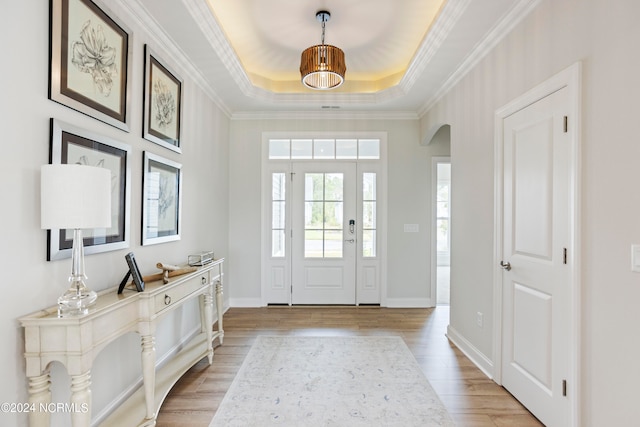 entryway featuring a raised ceiling, hardwood / wood-style flooring, and ornamental molding