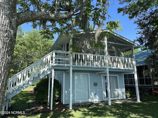 rear view of house featuring a sunroom and a lawn