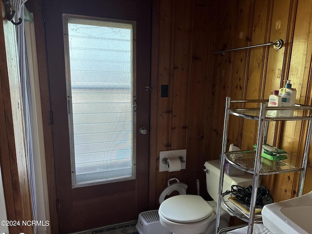 bathroom featuring wood walls and toilet