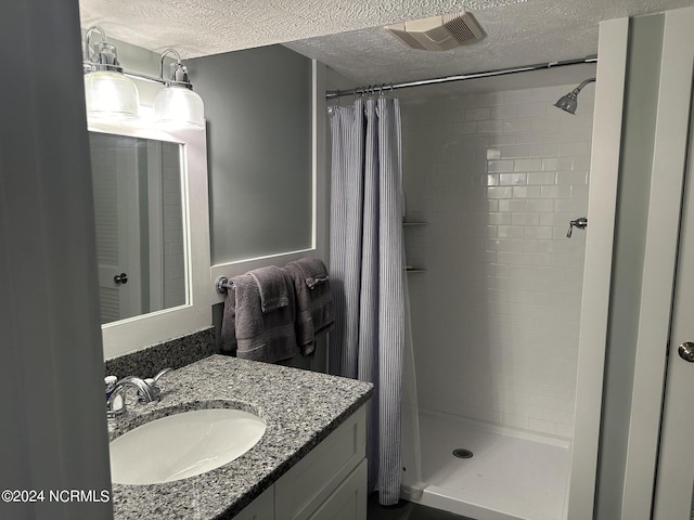 bathroom with a shower with shower curtain, a textured ceiling, and vanity