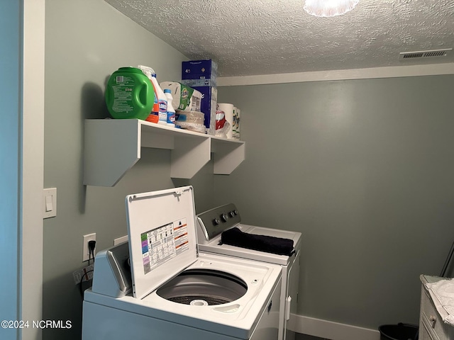 washroom featuring a textured ceiling and washer and clothes dryer