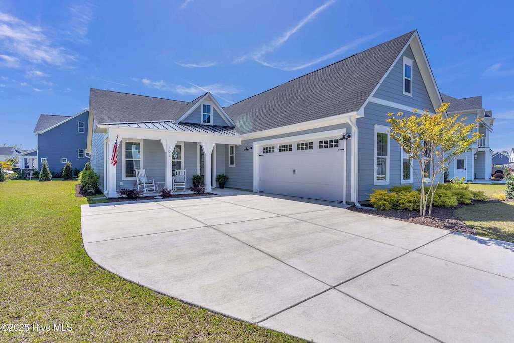 view of front of property with a front lawn, concrete driveway, a standing seam roof, covered porch, and a garage