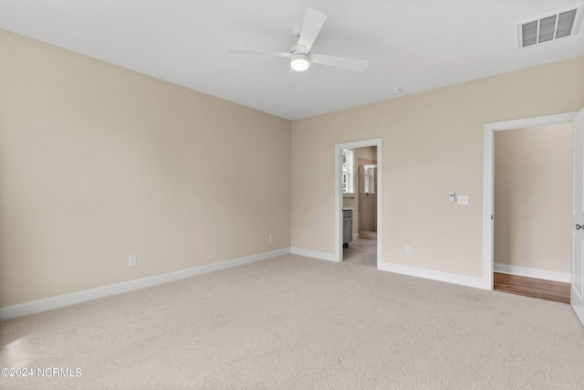 unfurnished bedroom featuring visible vents, connected bathroom, baseboards, ceiling fan, and light colored carpet