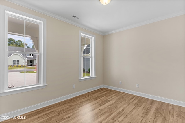 empty room featuring visible vents, baseboards, light wood-style floors, and crown molding