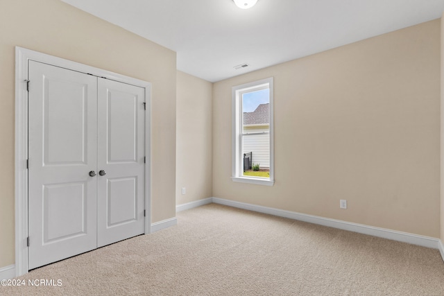 unfurnished bedroom featuring a closet, carpet flooring, baseboards, and visible vents