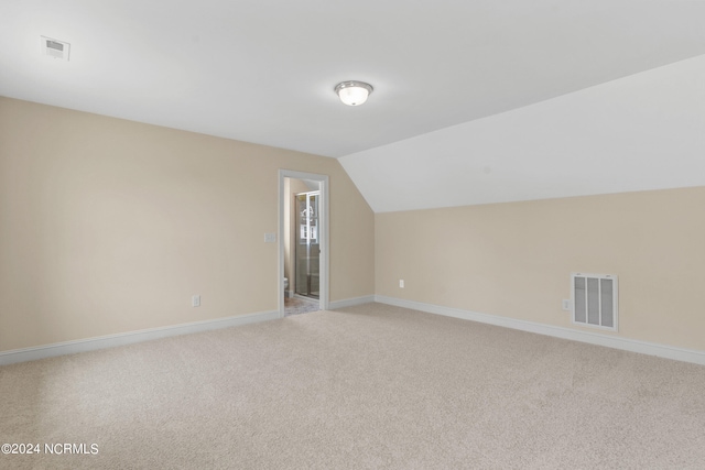 bonus room featuring visible vents, light carpet, baseboards, and vaulted ceiling