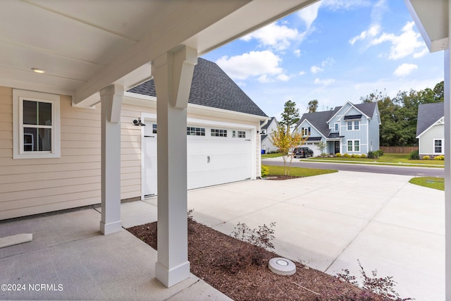 view of patio / terrace featuring a garage, a residential view, and concrete driveway