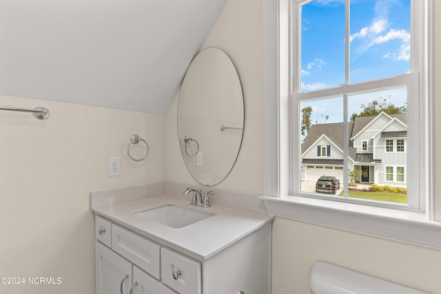 half bath with vanity, vaulted ceiling, and toilet