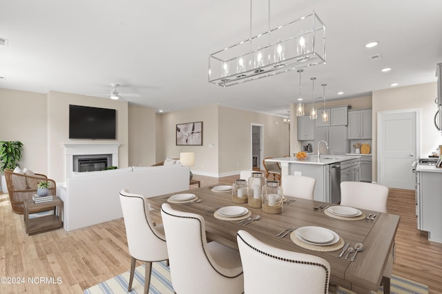 dining space featuring light wood-type flooring, visible vents, a glass covered fireplace, recessed lighting, and ceiling fan