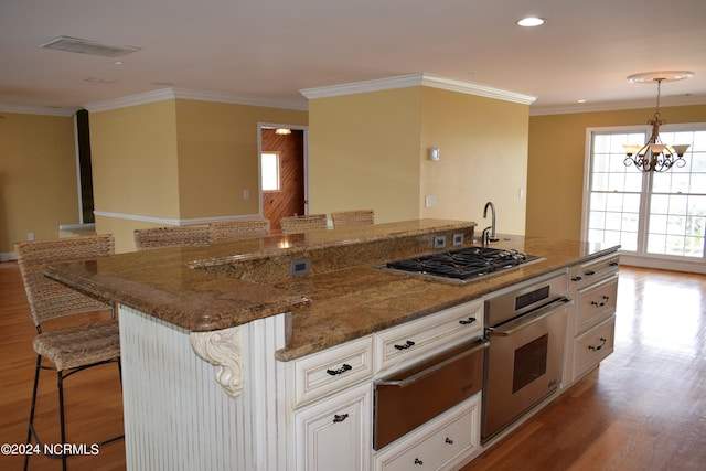 kitchen with an inviting chandelier, a kitchen breakfast bar, light hardwood / wood-style flooring, white cabinetry, and stainless steel appliances