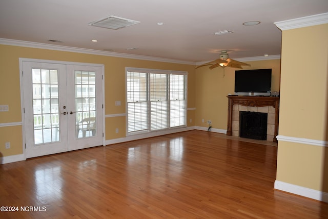 unfurnished living room with a tile fireplace, ceiling fan, french doors, hardwood / wood-style flooring, and ornamental molding