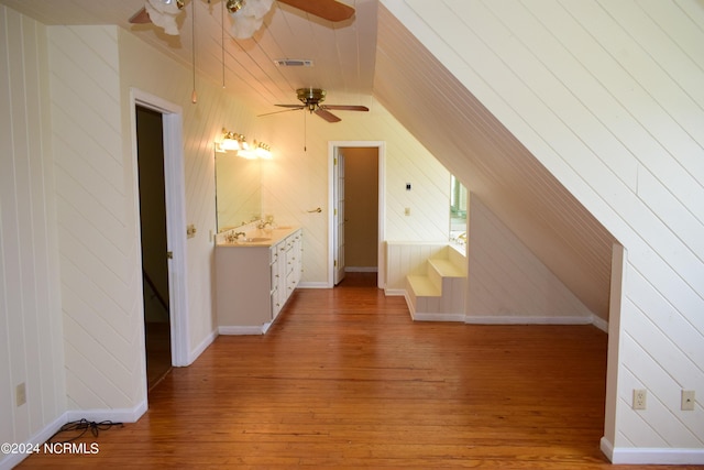 additional living space featuring hardwood / wood-style floors, vaulted ceiling, ceiling fan, and wooden walls