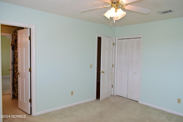 unfurnished bedroom with ceiling fan, a closet, and light colored carpet