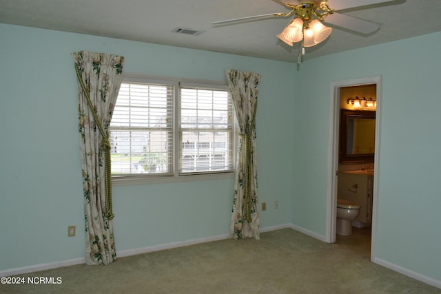 unfurnished bedroom featuring ceiling fan, light carpet, and ensuite bath