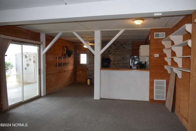 interior space featuring carpet, ceiling fan, and wooden walls