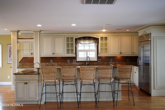 kitchen featuring built in fridge, cream cabinets, a center island, and light wood-type flooring