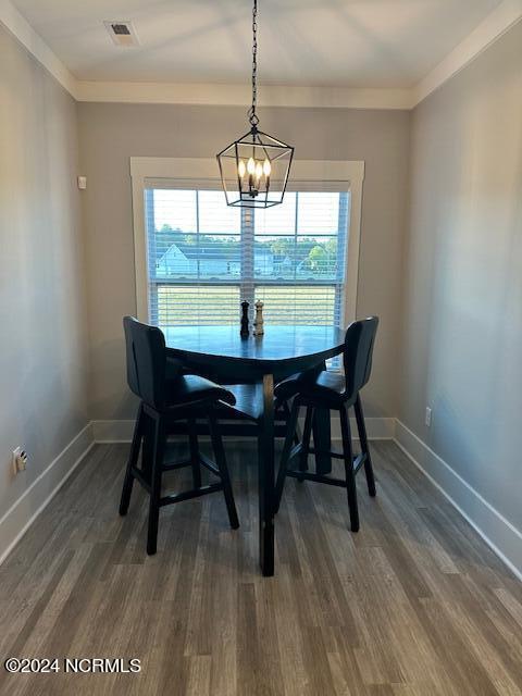 dining space featuring dark hardwood / wood-style flooring, crown molding, and a notable chandelier