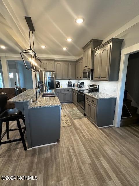 kitchen featuring hardwood / wood-style flooring, stainless steel appliances, and light stone counters