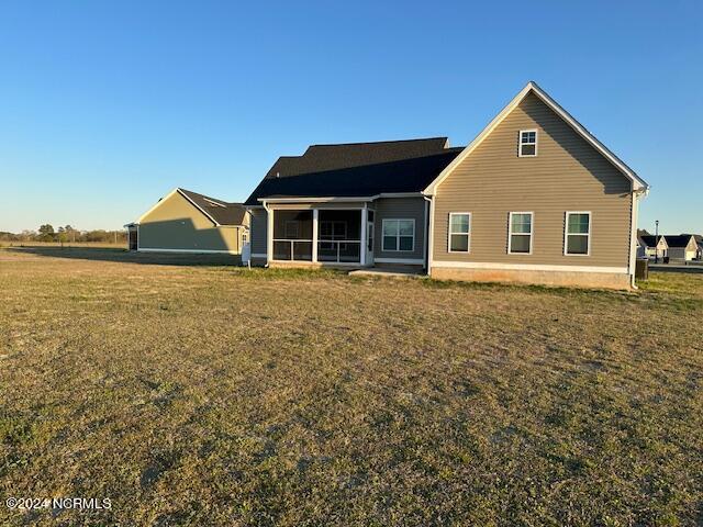 back of property featuring a sunroom and a lawn