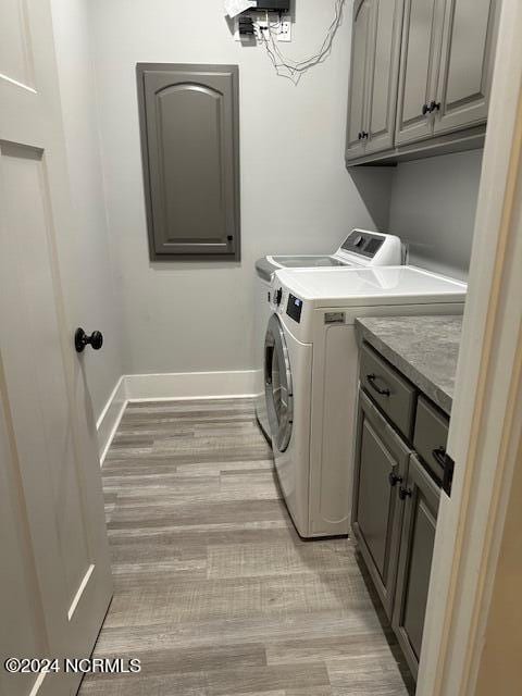 laundry area with light hardwood / wood-style flooring, cabinets, and washer and dryer