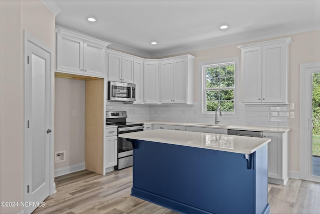 kitchen with white cabinets, sink, appliances with stainless steel finishes, and light hardwood / wood-style flooring