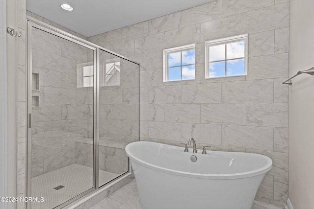 bathroom featuring shower with separate bathtub and tile walls